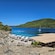 A small beach with umbrellas and lounge chairs next to the water and rocky coastline of a bay in Dubrovnik, Croatia